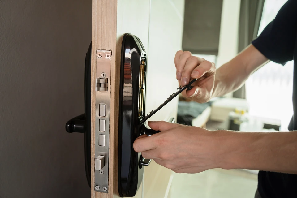 Intérieur résidentiel, technicien installant une serrure électronique sur porte d'entrée