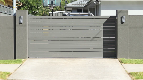 Entrée de propriété avec portail automatique blanc à double battant en PVC ou aluminium laqué, piliers blancs à chapiteaux pyramidaux