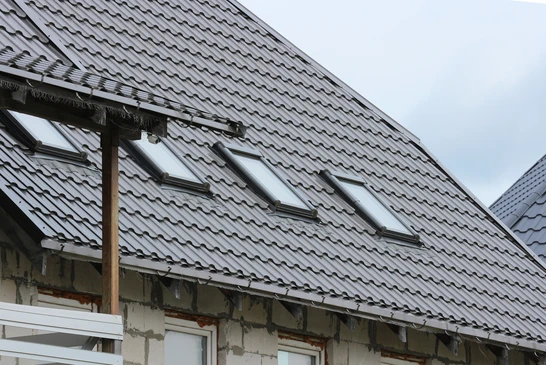 Façade moderne de maison individuelle avec volets roulants marron fermés sur baie vitrée d'angle