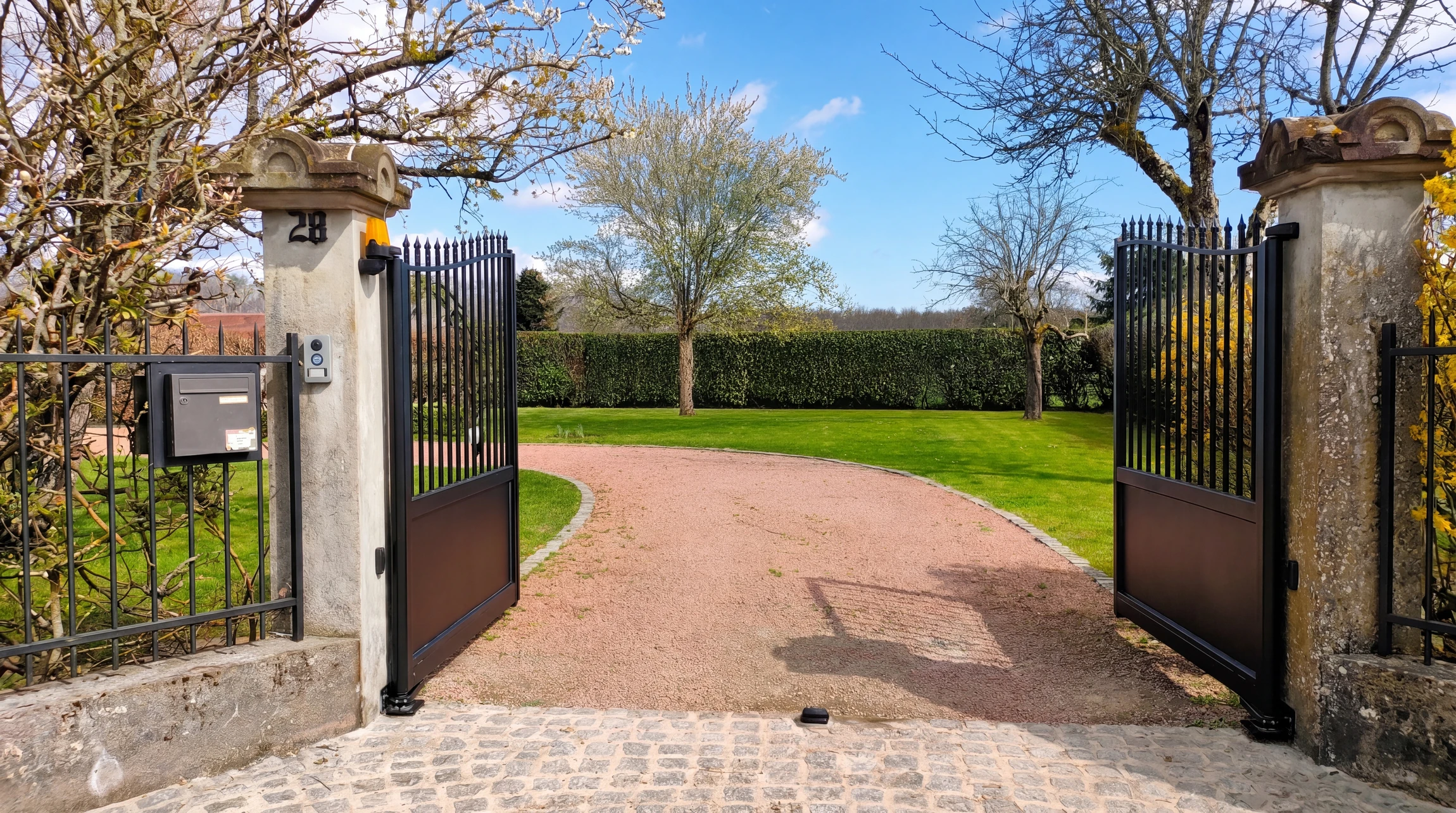 Entrée extérieure d'habitation avec porte en bois peinte anthracite équipée d'un heurtoir décoratif en fer forgé