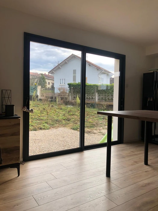 Entrée de maison avec porte d'entrée en PVC blanc, vitrage dépoli pleine hauteur à arc en ogive, poignée en inox, serrure à cylindre