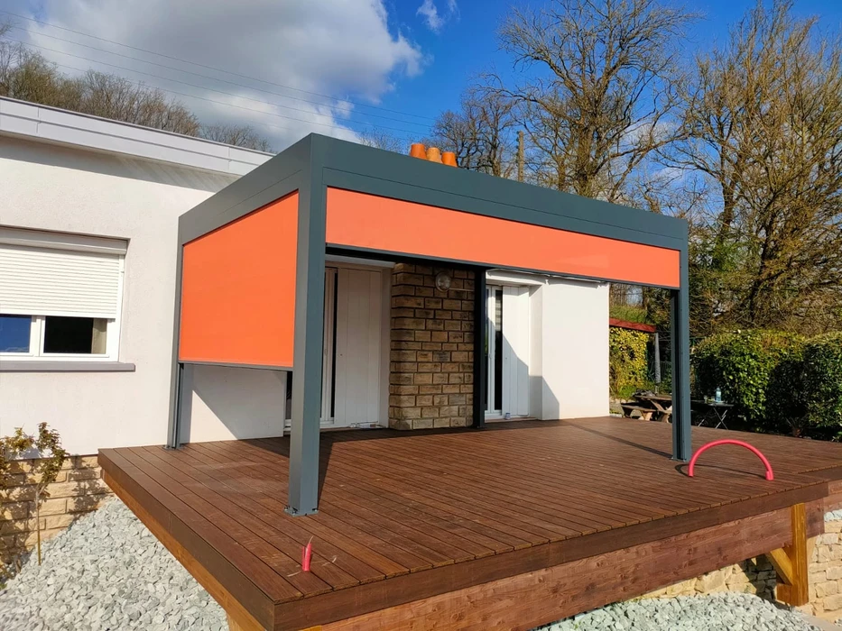 Terrasse moderne en dallage béton avec pergola bioclimatique aluminium anthracite à lames orientables, adossée à une maison contemporaine
