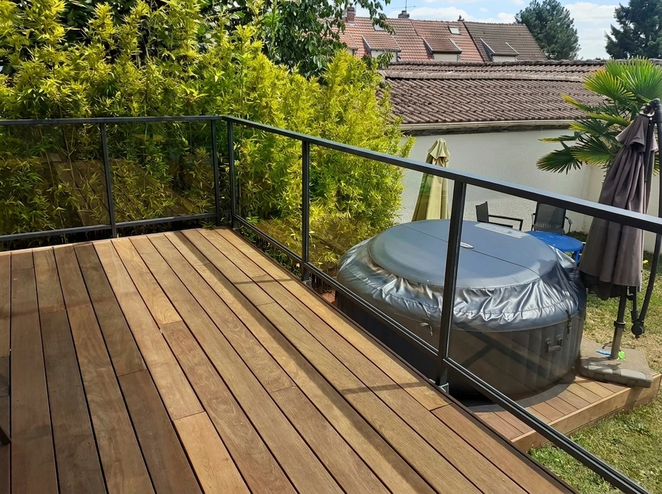 Terrasse extérieure couverte par une pergola bioclimatique à lames orientables en aluminium anodisé gris, fixée en applique murale