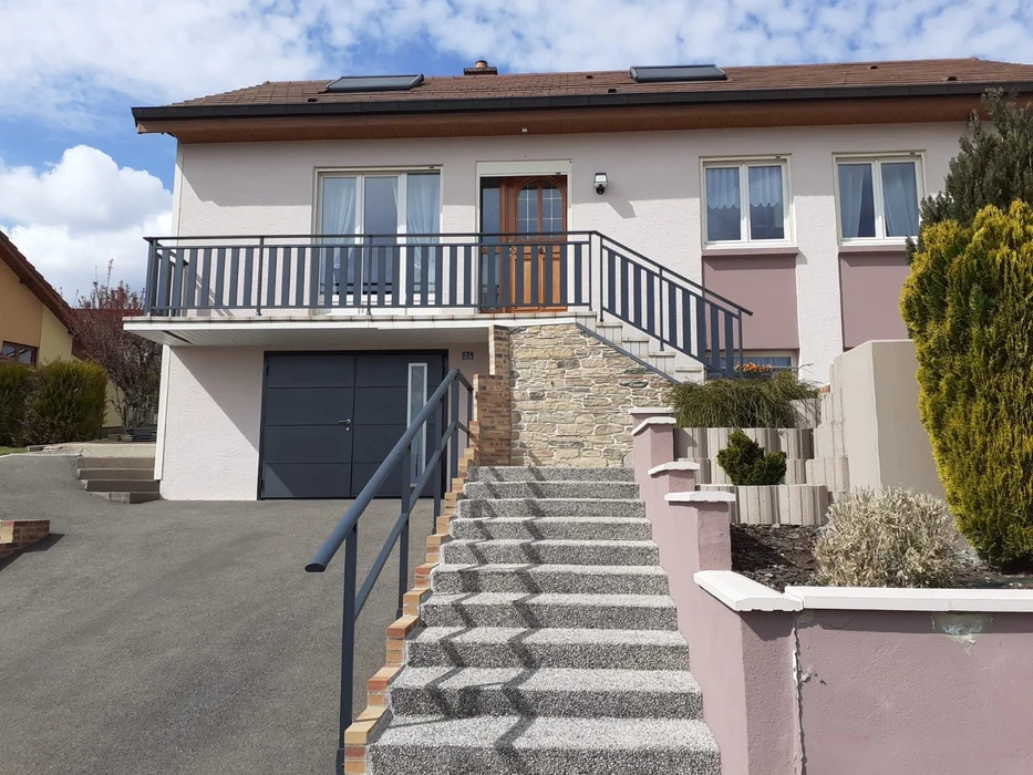 Terrasse moderne en dallage béton avec pergola bioclimatique aluminium anthracite à lames orientables, adossée à une maison contemporaine