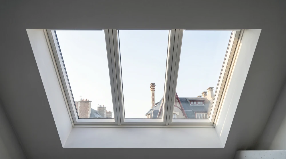 Véranda intérieure avec structure en bois lamellé-collé, toiture à deux pans avec faîtage apparent, lambris blanc en sous-face